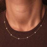 Gold-plated sterling silver station necklace with small clear cubic zirconia floral motifs worn around the neck