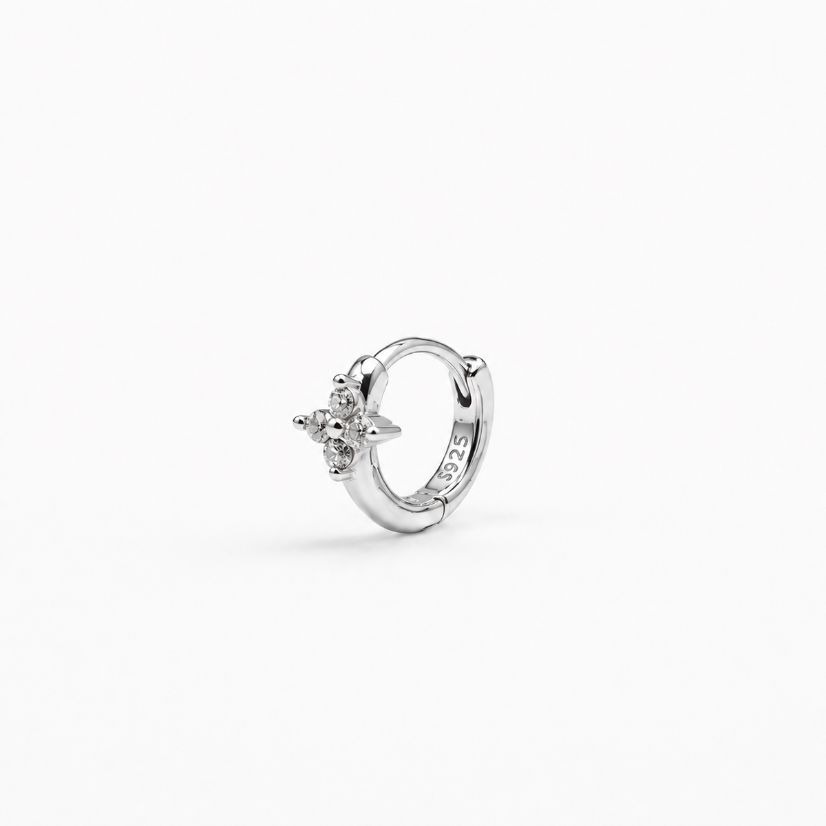 Rhodium-plated sterling silver flower huggie earring with clear cubic zirconia stones worn on the ear.