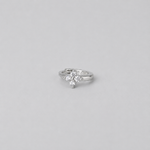 Rhodium-plated sterling silver flower huggie earring with clear cubic zirconia stones worn on the ear.