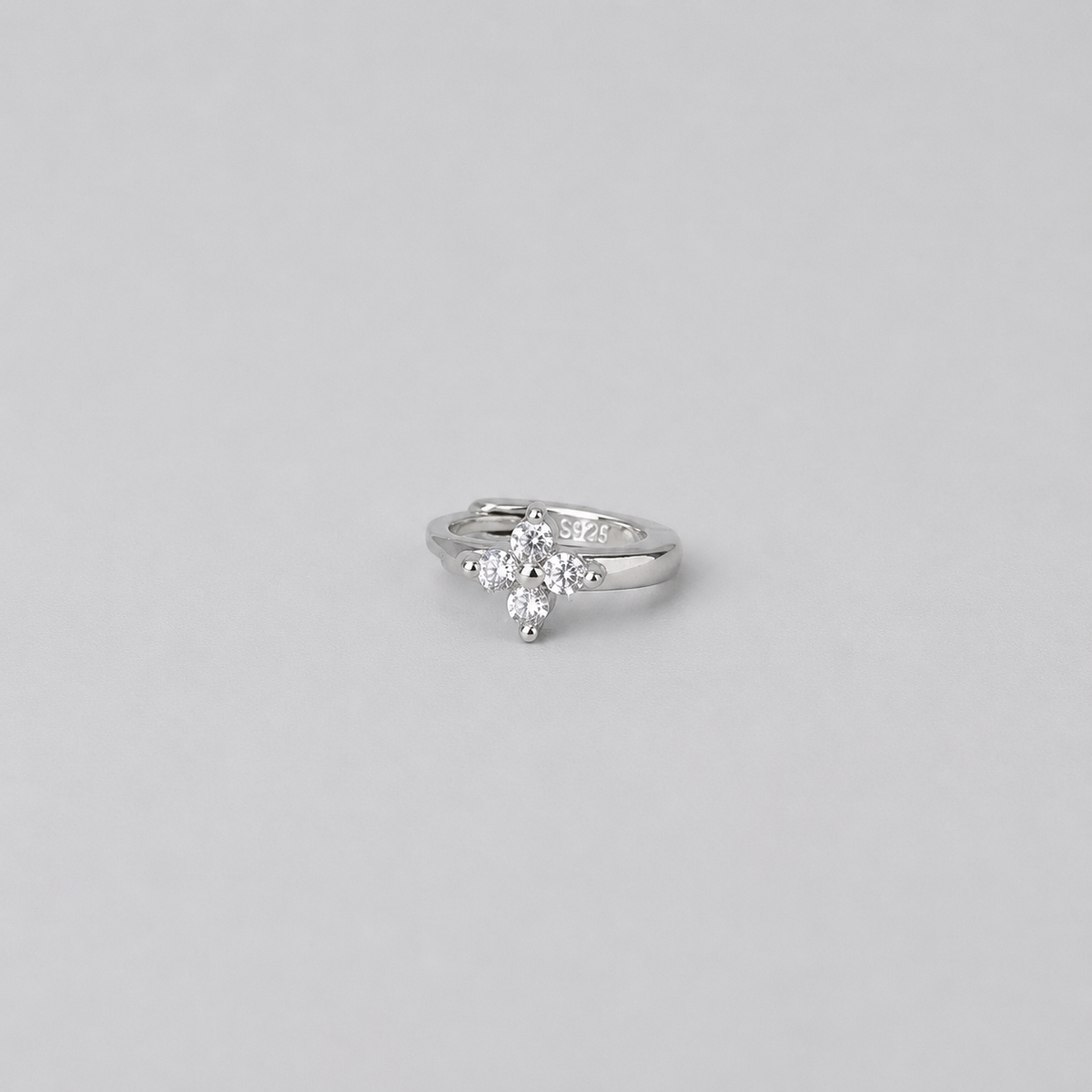 Rhodium-plated sterling silver flower huggie earring with clear cubic zirconia stones worn on the ear.
