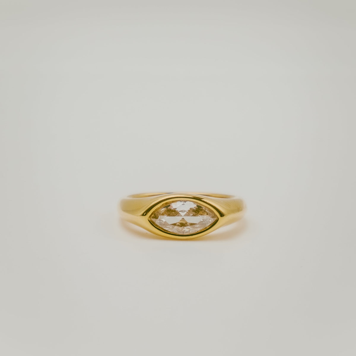 Bague en argent 925 plaqué or avec pierre centrale taille marquise sertie sur un anneau épais, sur fond clair
