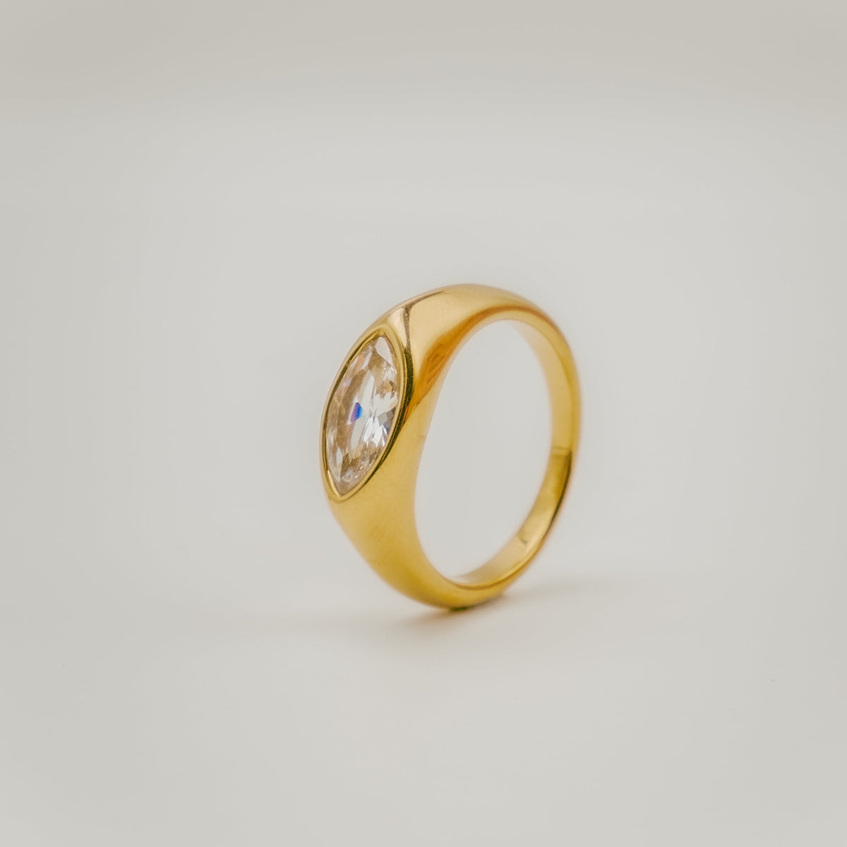 Bague en argent 925 plaqué or avec pierre centrale taille marquise sertie sur un anneau épais, sur fond clair