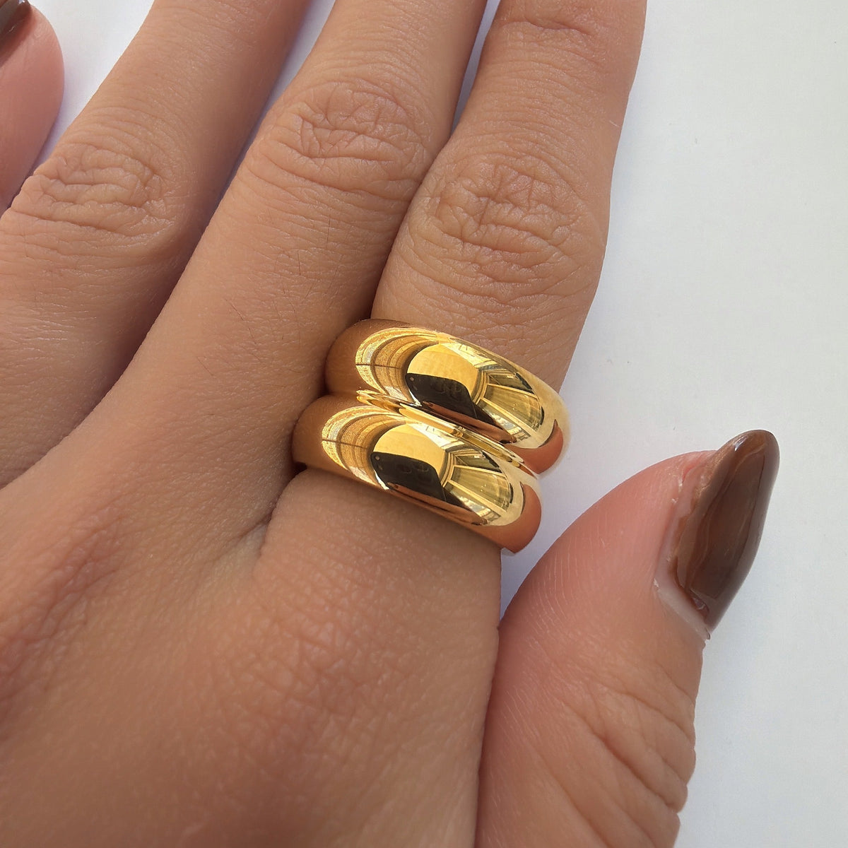 Bague dorée à double anneau bombé avec finition lisse et brillante, portée au doigt