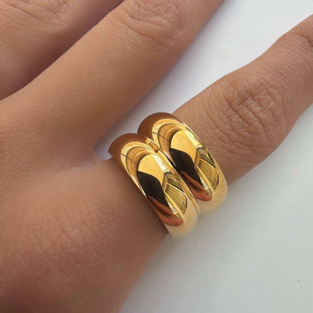 Bague dorée à double anneau bombé avec finition lisse et brillante, portée au doigt