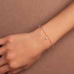 Bracelet en argent 925 plaqué or avec petits motifs fleur sertis d’oxydes de zirconium, porté au poignet