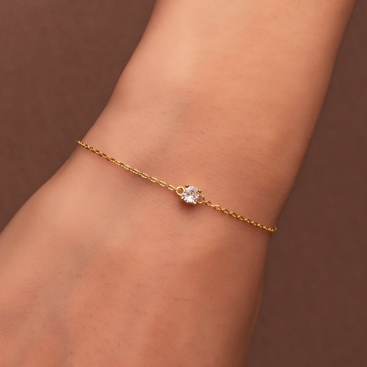 Bracelet délicat en argent 925 plaqué or avec pierre solitaire en oxyde de zirconium transparent, porté au poignet