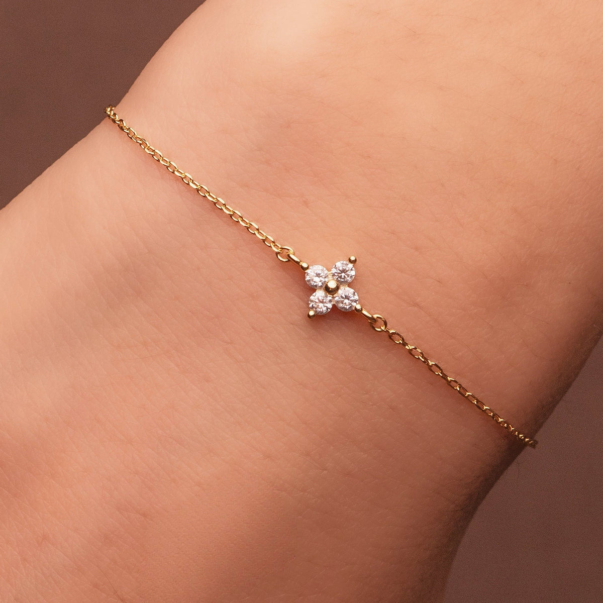 Bracelet en argent 925 plaqué or avec motif trèfle serti d’oxydes de zirconium transparents, porté au poignet