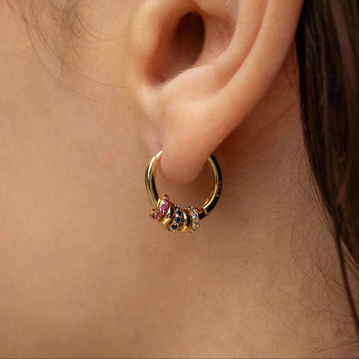 Créole en acier inoxydable plaqué or avec petits anneaux sertis de pierres multicolores, portée à l’oreille