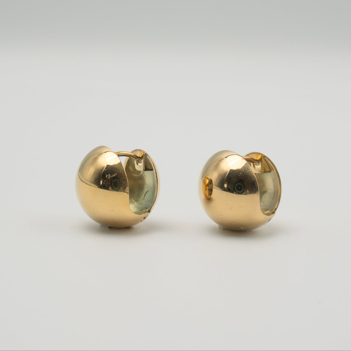 Boucles d’oreilles créoles rondes et bombées en acier inoxydable plaqué or, finition brillante, sur fond clair