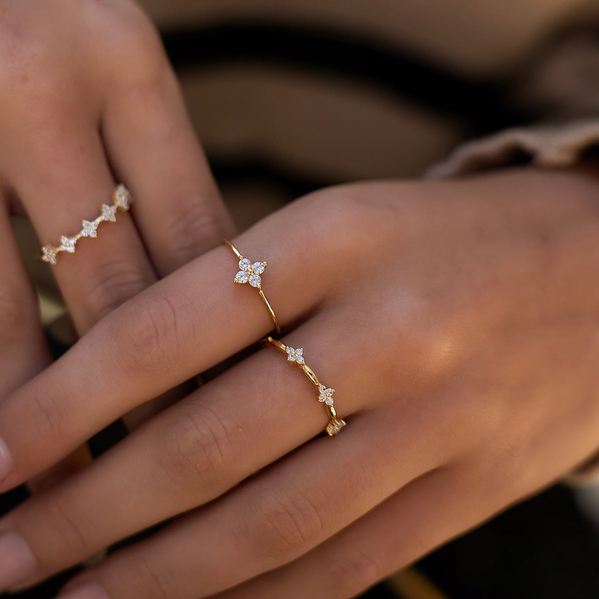 Gold-plated sterling silver flower ring stack with clear cubic zirconia stones worn on the finger.