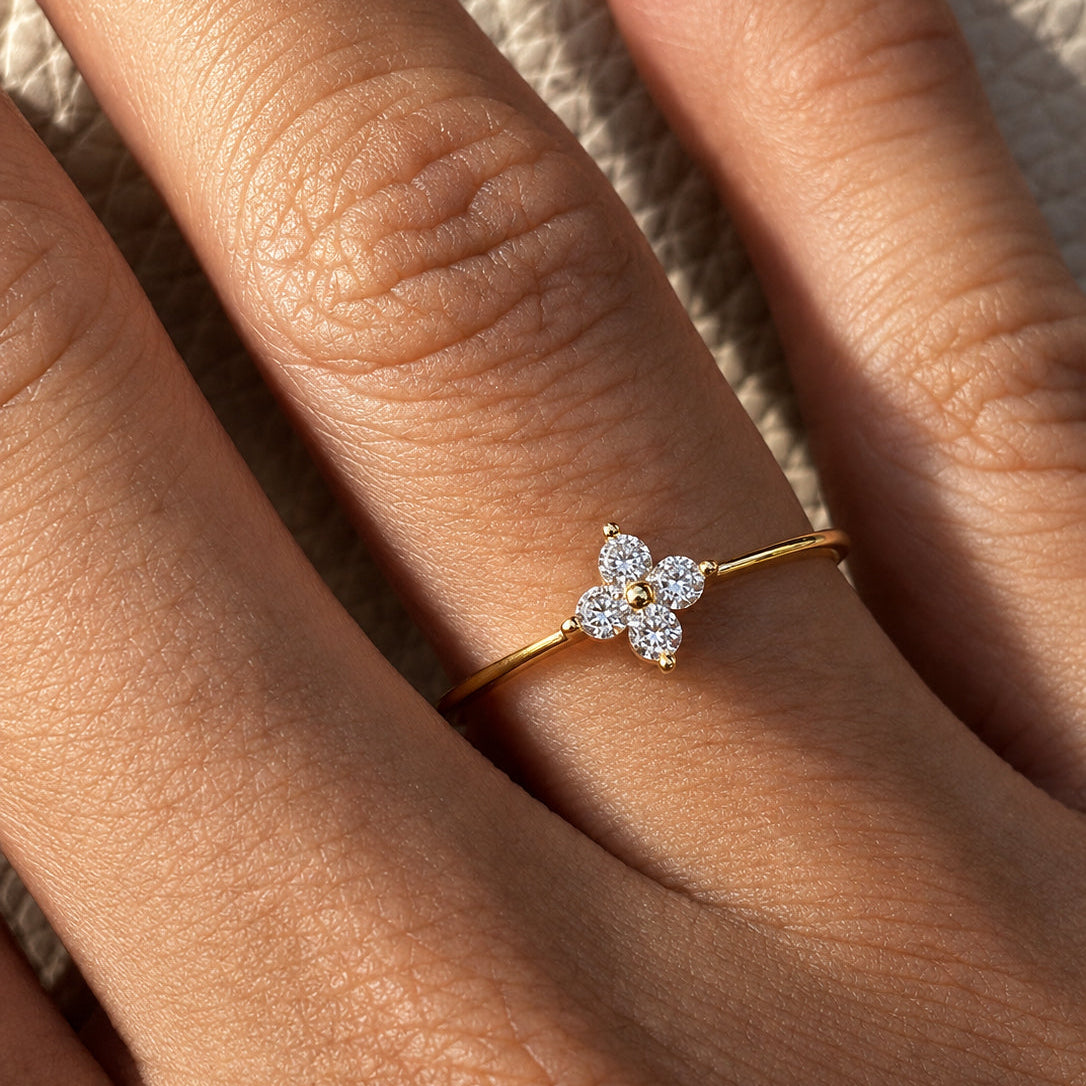 Gold-plated sterling silver flower ring with clear cubic zirconia stones worn on the finger.