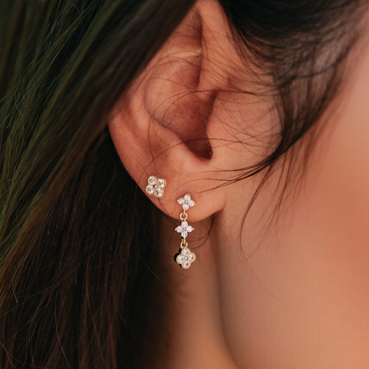 Gold-plated stainless steel drop earrings with clear cubic zirconia floral clusters worn on the ear