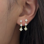 Gold-plated stainless steel drop earrings with clear cubic zirconia floral clusters worn on the ear