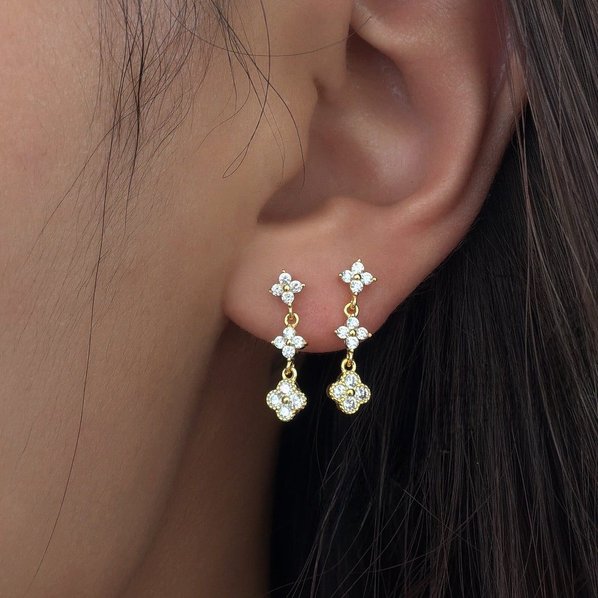 Gold-plated stainless steel drop earrings with clear cubic zirconia floral clusters worn on the ear