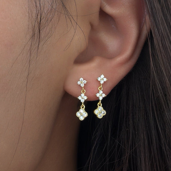 Gold-plated stainless steel drop earrings with clear cubic zirconia floral clusters worn on the ear