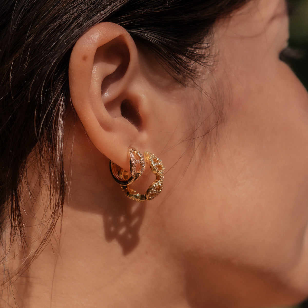 Gold-plated stainless steel huggie earrings with pavé cubic zirconia link details worn on the ear