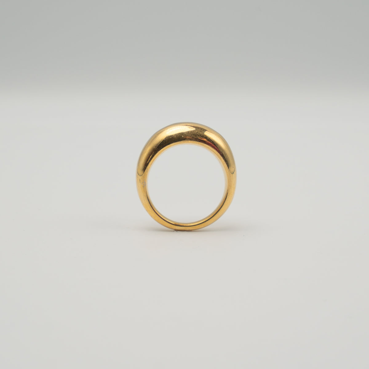 Gold-plated stainless steel smooth dome ring with a polished finish on a light background