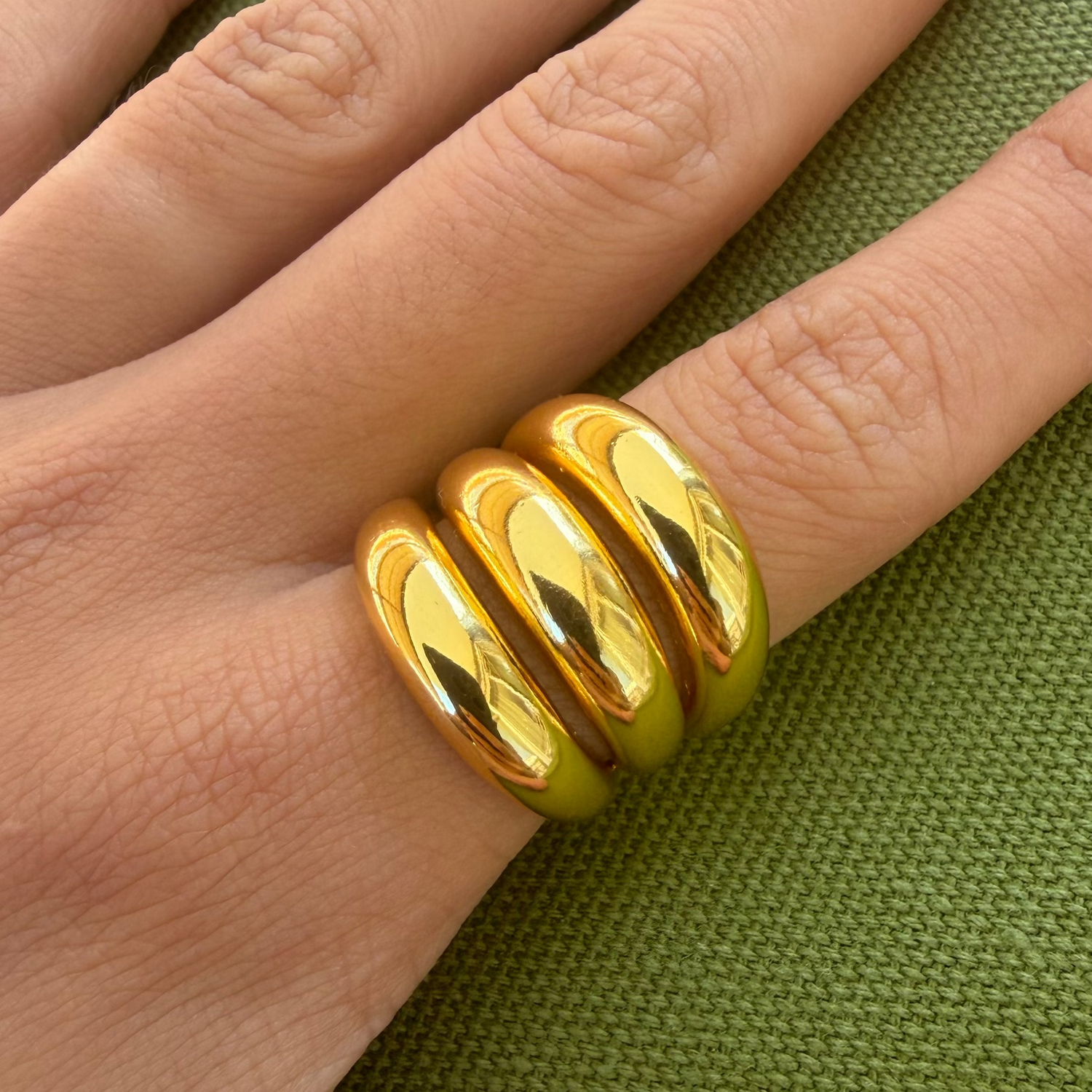 Gold-plated stainless steel chunky ring with three rounded stacked bands worn on the finger