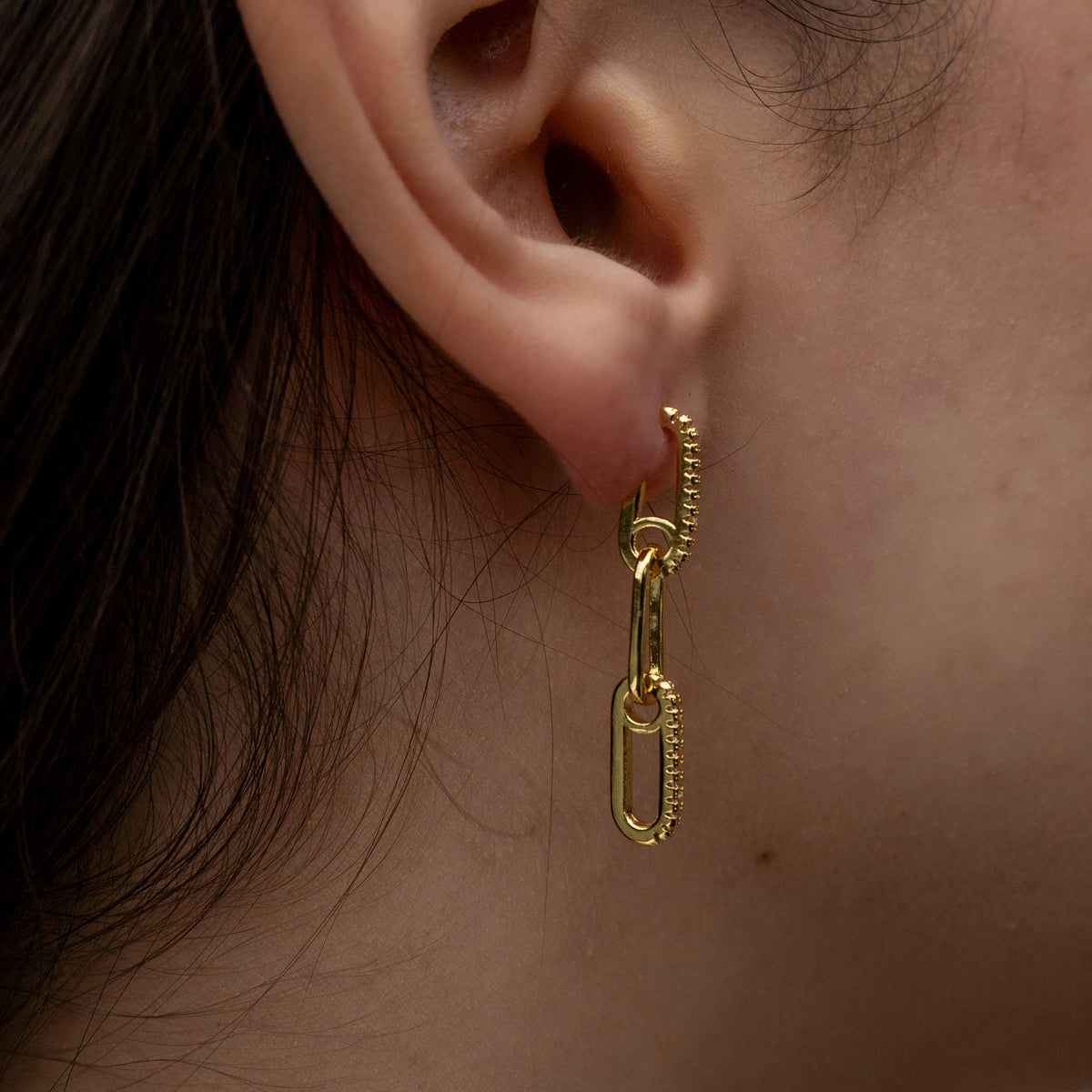 Gold-plated sterling silver drop earrings with elongated chain-link details and clear cubic zirconia accents worn on the ear