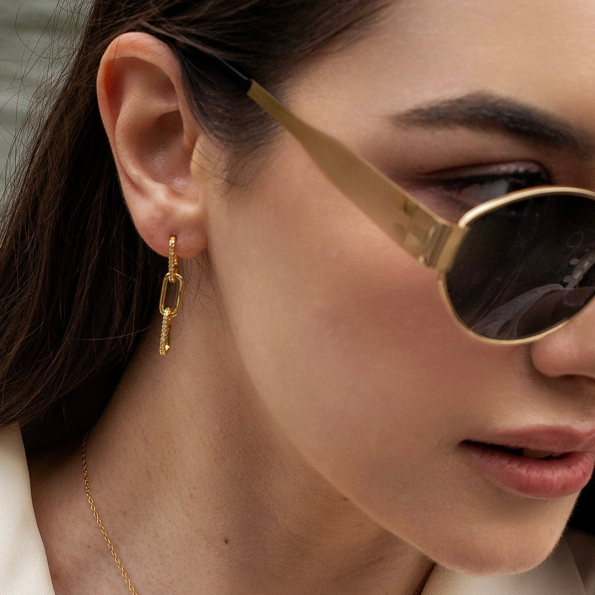 Gold-plated sterling silver drop earrings with elongated chain-link details and clear cubic zirconia accents worn on the ear
