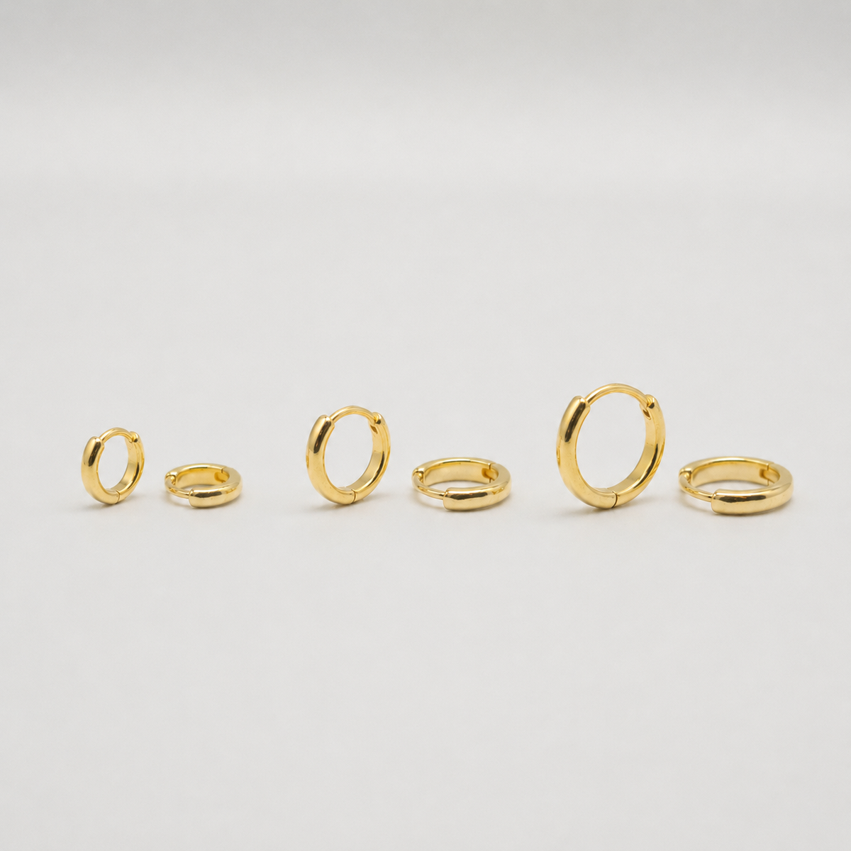 Gold-plated sterling silver classic huggie hoop earrings with a smooth polished finish on a light background