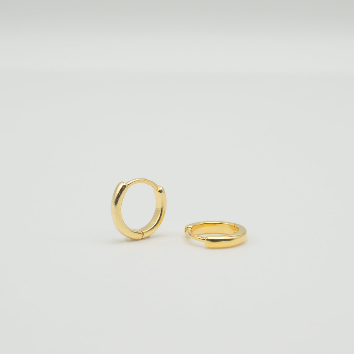 Gold-plated sterling silver classic huggie hoop earrings with a smooth polished finish on a light background