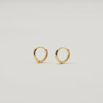 Gold-plated sterling silver classic huggie hoop earrings with a smooth polished finish on a light background