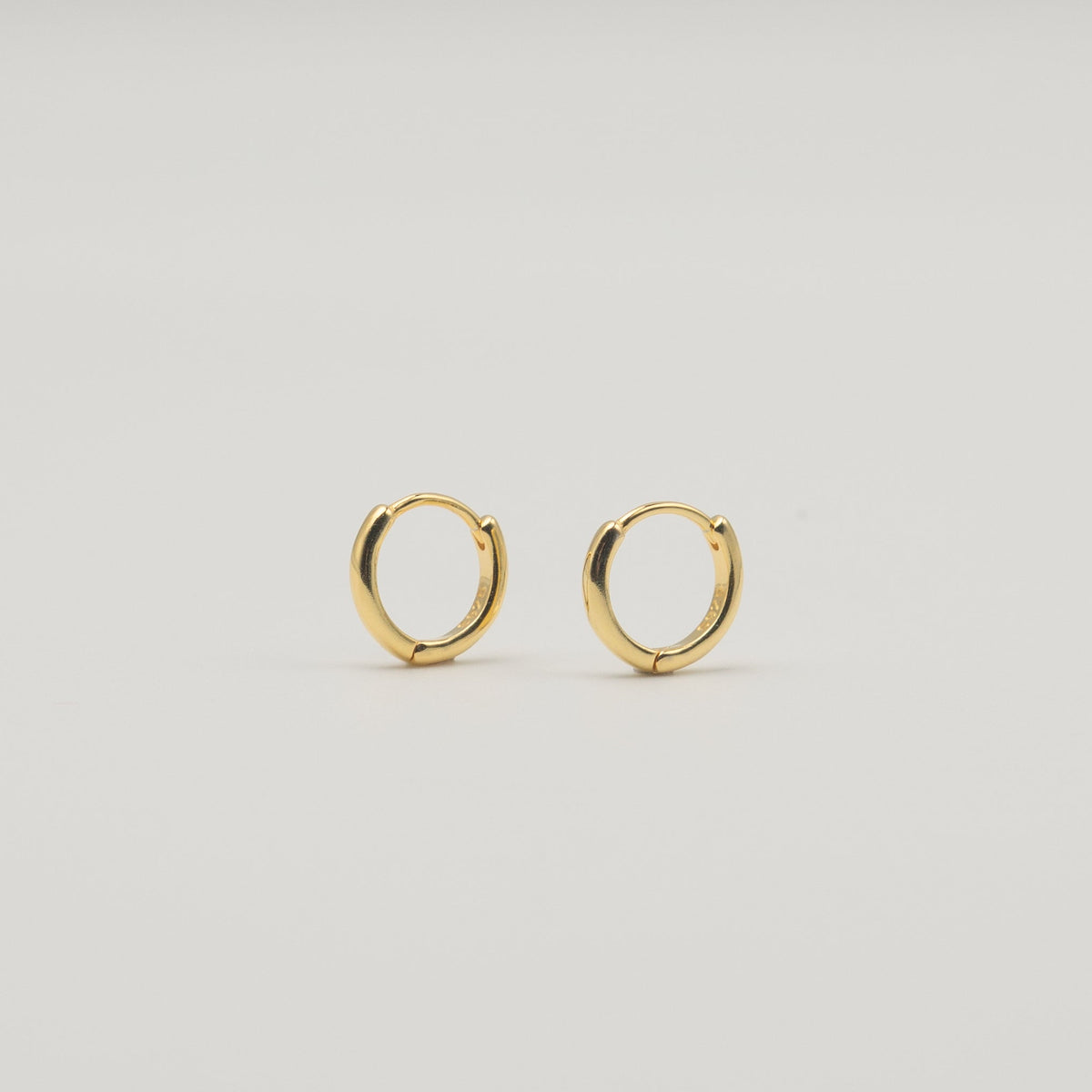Gold-plated sterling silver classic huggie hoop earrings with a smooth polished finish on a light background