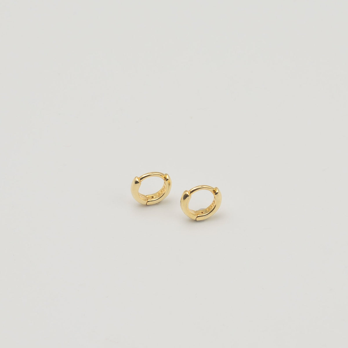Gold-plated sterling silver classic huggie hoop earrings with a smooth polished finish on a light background
