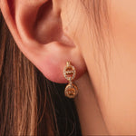 Gold-plated sterling silver drop earrings with double circular cubic zirconia details worn on the ear