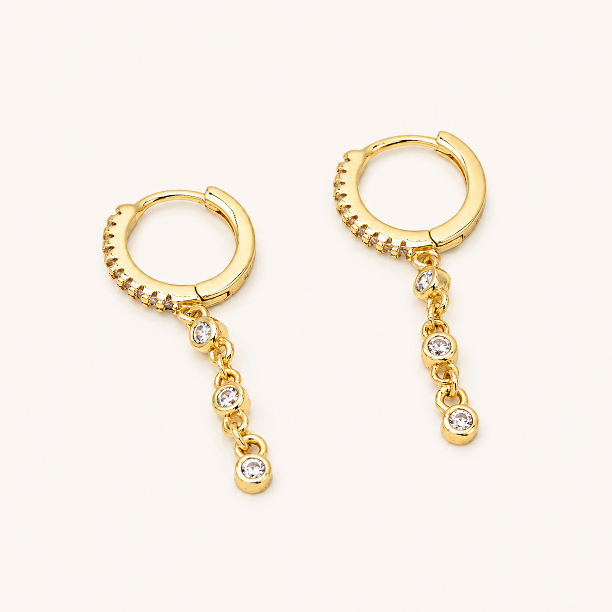 Gold-plated sterling silver huggie earring with pavé cubic zirconia and a dangling row of round cubic zirconia stones