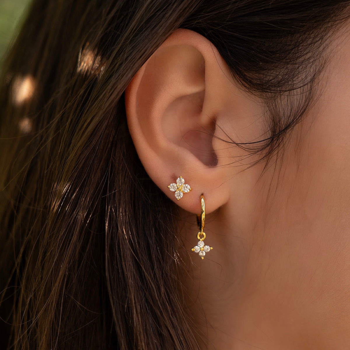 Gold-plated sterling silver hoop earrings with clear cubic zirconia star-shaped drops worn on the ear