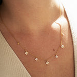 Gold-plated sterling silver necklace with five small clear cubic zirconia flower charms worn around the neck