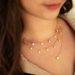 Gold-plated sterling silver necklace with five small clear cubic zirconia flower charms worn around the neck