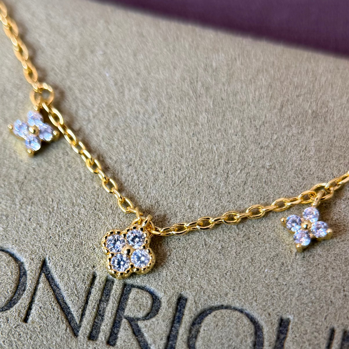 Gold-plated sterling silver necklace with five small clear cubic zirconia flower charms 