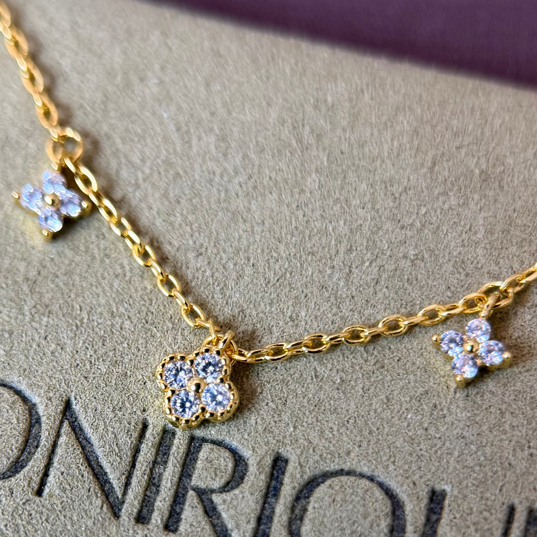 Gold-plated sterling silver necklace with five small clear cubic zirconia flower charms 