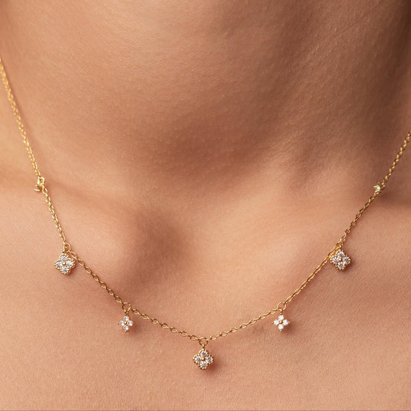 Gold-plated sterling silver necklace with five small clear cubic zirconia flower charms worn around the neck