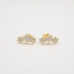 Gold-plated sterling silver stud earrings with clustered floral cubic zirconia details on a light background