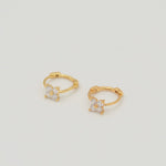 Gold-plated sterling silver huggie earrings with four-petal cubic zirconia flower details on a light background