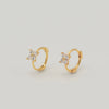 Gold-plated sterling silver huggie earrings with four-petal cubic zirconia flower details on a light background