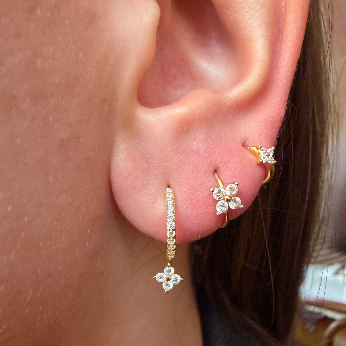 Gold-plated sterling silver flower ear stack with clear cubic zirconia stones worn on the ear.