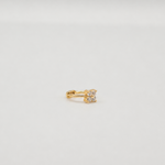 Gold-plated sterling silver huggie earring with a clear cubic zirconia flower detail worn on the ear