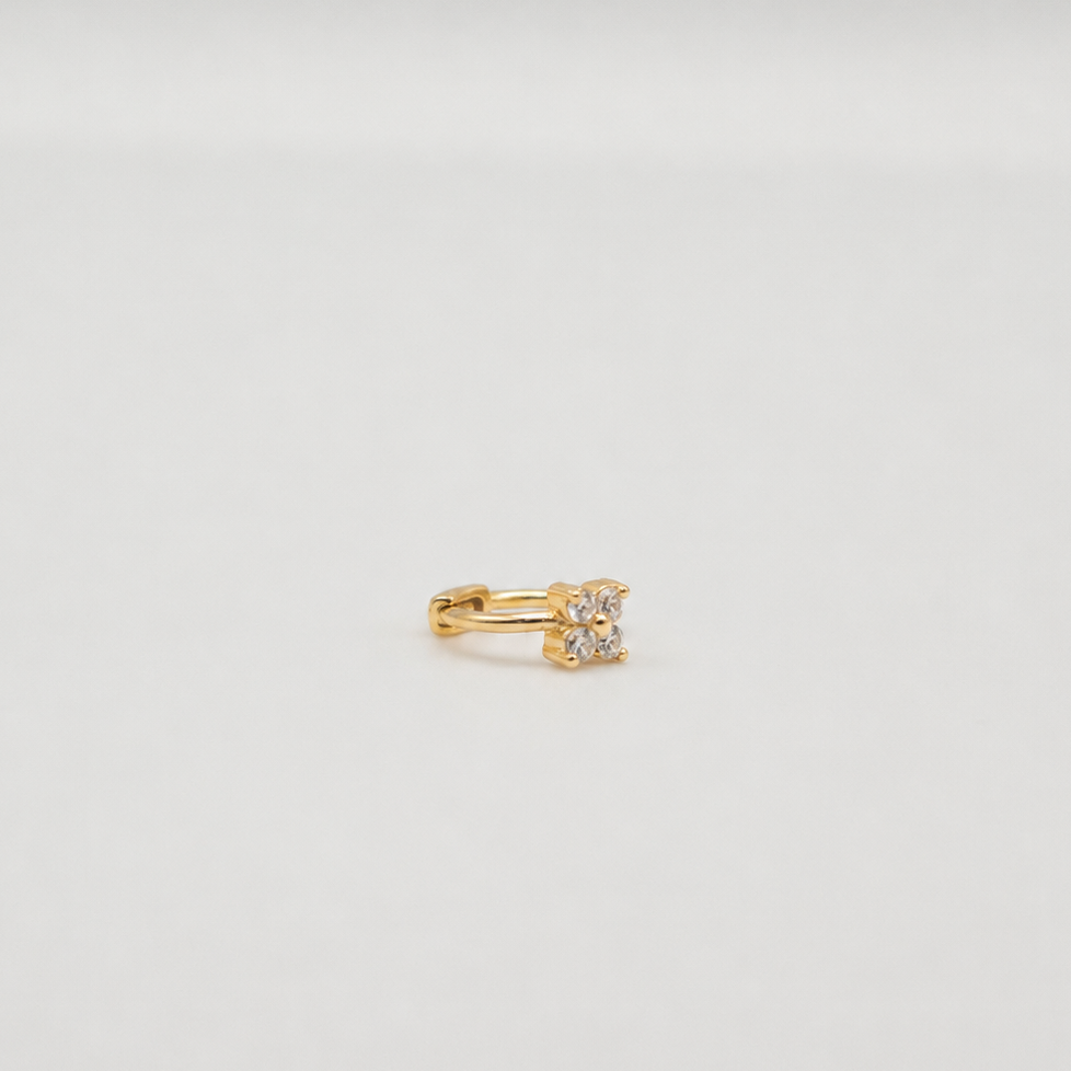 Gold-plated sterling silver huggie earring with a clear cubic zirconia flower detail worn on the ear