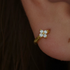 Gold-plated sterling silver flower huggie earring with clear cubic zirconia stones worn on the ear.