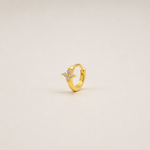 Gold-plated sterling silver flower huggie earring with clear cubic zirconia stones worn on the ear.