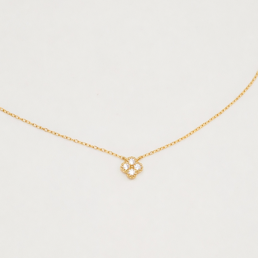 Gold-plated sterling silver necklace with a four-petal cubic zirconia pendant on a light background
