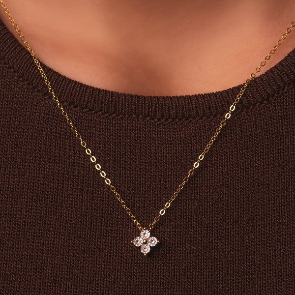 Gold-plated sterling silver necklace with a four-petal clear cubic zirconia pendant worn around the neck