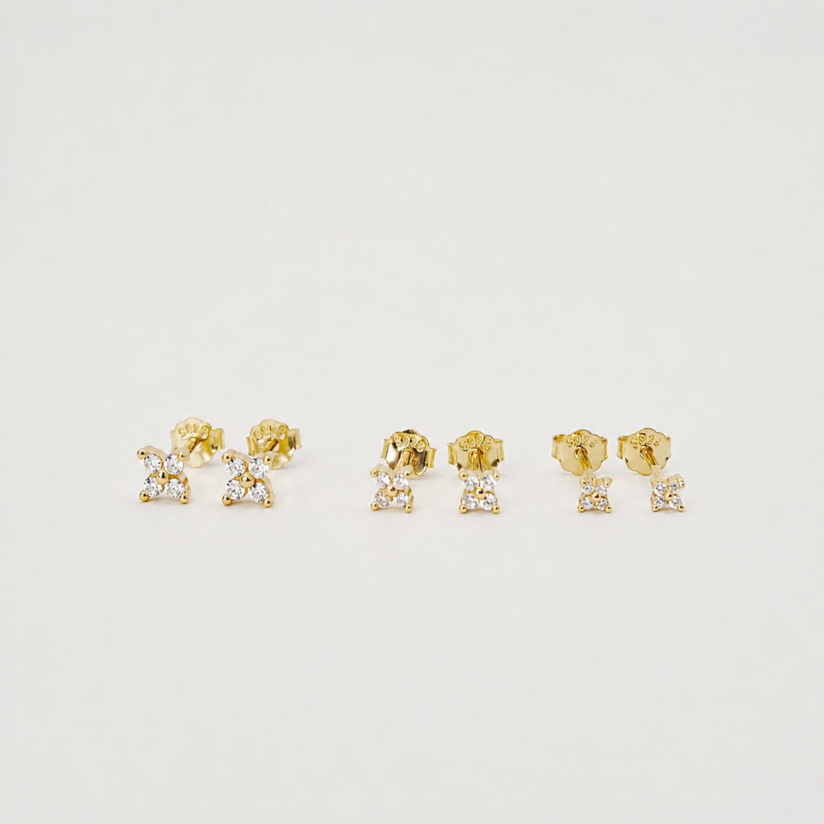 Gold-plated sterling silver stud earrings with four-petal clear cubic zirconia designs 