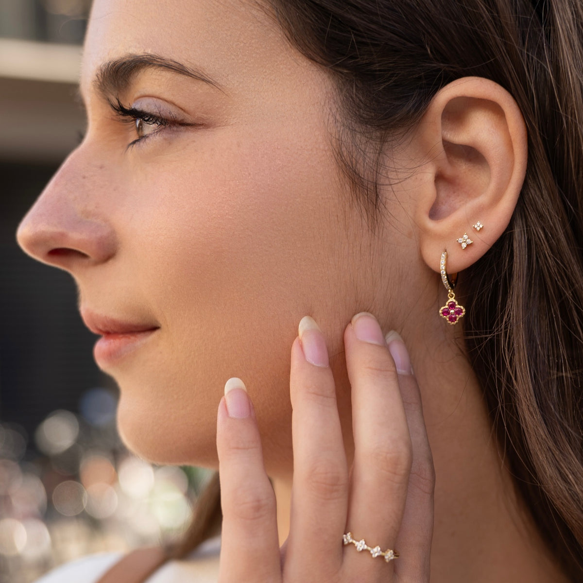 Gold-plated sterling silver stud earrings with four-petal clear cubic zirconia designs worn on the ear