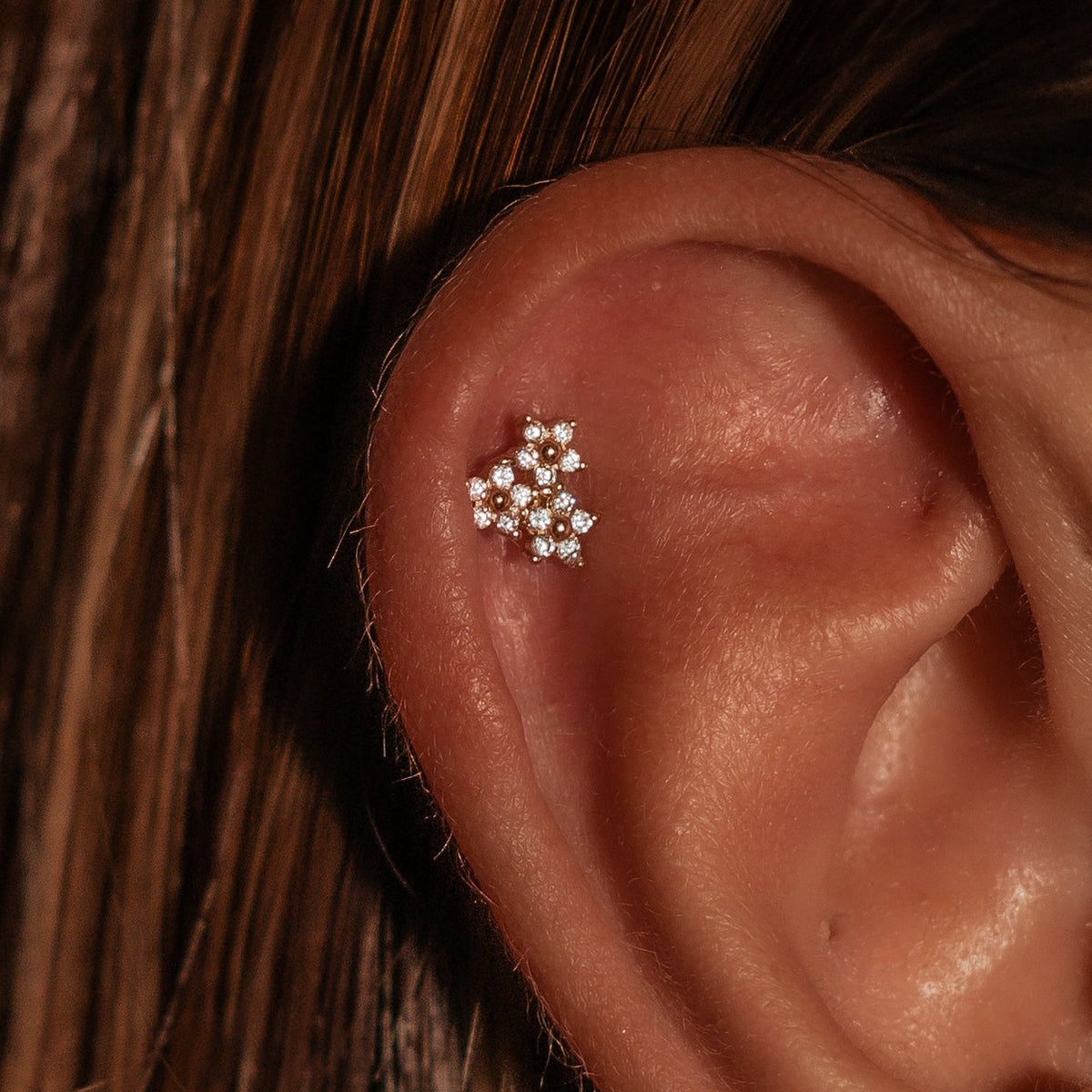 Gold-plated sterling silver huggie earring with a four-petal clear cubic zirconia flower design